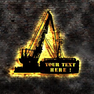 Könnte beinhalten: Eine Silhouette eines Krans mit einem gelben Schein dahinter. Der Kran steht vor einem Hintergrund aus Ziegelmauer. Der Text "YOUR TEXT HERE!" befindet sich in der unteren rechten Ecke des Bildes.