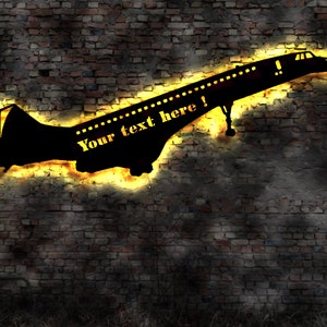 Pode incluir: Uma silhueta preta de um avião supersônico com o texto "Your text here!" em amarelo sobre um fundo de parede de tijolo.