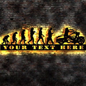 May include: Black metal wall art depicting the evolution of man, culminating in a person riding a motorcycle. The art features the text "YOUR TEXT HERE" in a bold, blocky font.