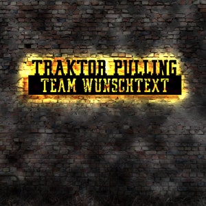 Op de afbeelding: Een geel neonbord op een bakstenen muur met de tekst "Traktor Pulling Team Wunschtext".