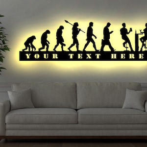 Peut inclure: Décoration murale en métal noir représentant l'évolution de l'homme, d'un singe primitif à un homme moderne tenant un smartphone. L'œuvre d'art comprend le texte "YOUR TEXT HERE".