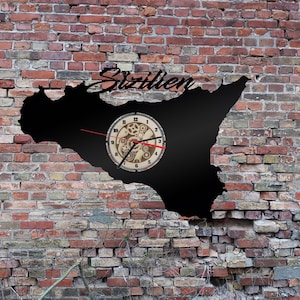 Può includere: Una silhouette nera dell'isola di Sicilia con la parola "Sicilien" scritta sopra. Un orologio con un design a ingranaggi è integrato nella silhouette.