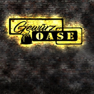 Könnte beinhalten: Ein gelbes Neon-Schild mit dem Text "Gewürz Oase" an einer Backsteinwand. Das Schild hat eine Silhouette eines Gewürzsacks.