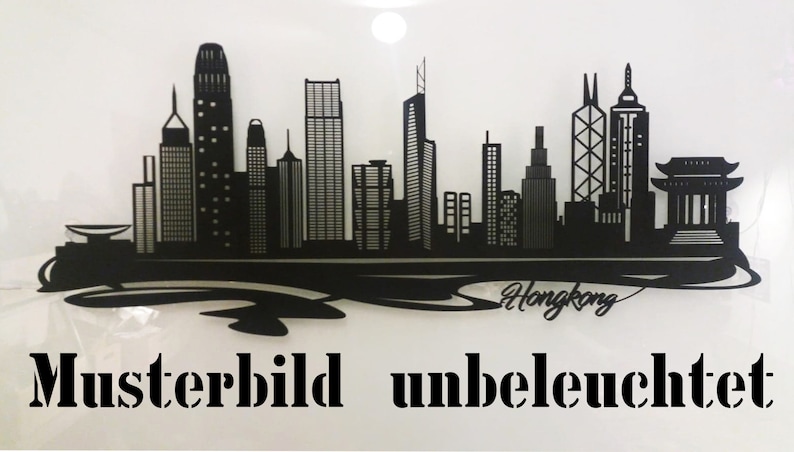 May include: Black silhouette of the Hong Kong skyline with the word "Hongkong" written underneath. The image is labelled "Musterbild unbeleuchtet" which translates to "Sample image unlit".