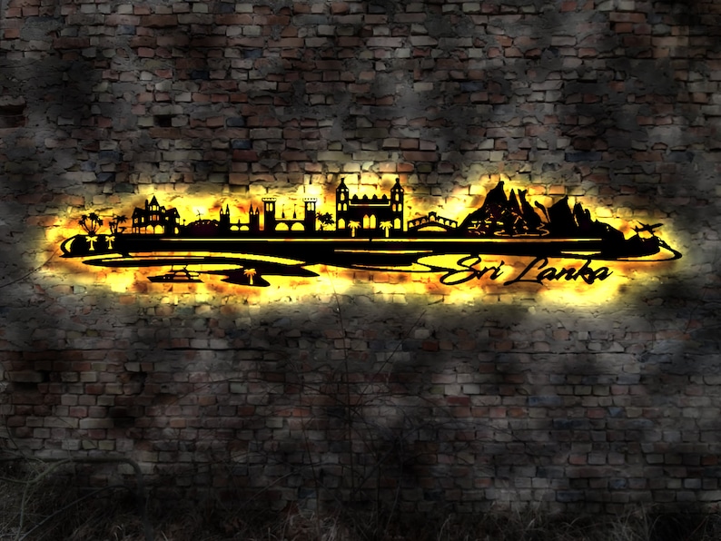 May include: A black metal silhouette of the Sri Lankan skyline featuring buildings, bridges, and palm trees. The silhouette is illuminated from behind with a warm yellow glow, creating a dramatic effect. The words "Sri Lanka" are written in a stylised font below the silhouette.