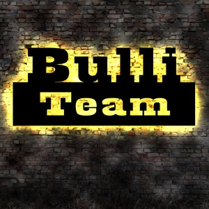 May include: A black and yellow neon sign on a brick wall reads "Bulli Team".