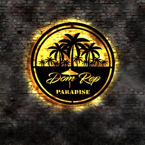 May include: A black and yellow circular sign with palm trees and the text "Dom Rep Paradise" on a brick wall background.