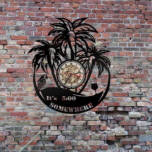 May include: Black metal wall clock with a palm tree design and the text "It's 5:00 Somewhere". The clock face is a round wooden clock with gears and a red second hand.