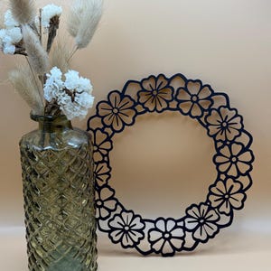 Könnte beinhalten: Ein schwarzer Blumenkranz mit einem filigranen Design, perfekt, um Ihrem Zuhause einen Hauch von rustikalem Charme zu verleihen.