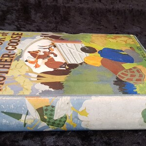 Op de afbeelding: Een vintage hardcover boek getiteld "The Big Book of Mother Goose". De omslag toont kleurrijke illustraties van kinderrijmkarakters en sc&egrave;nes. De rug van het boek toont de titel en de naam van de uitgever, Oxford.
