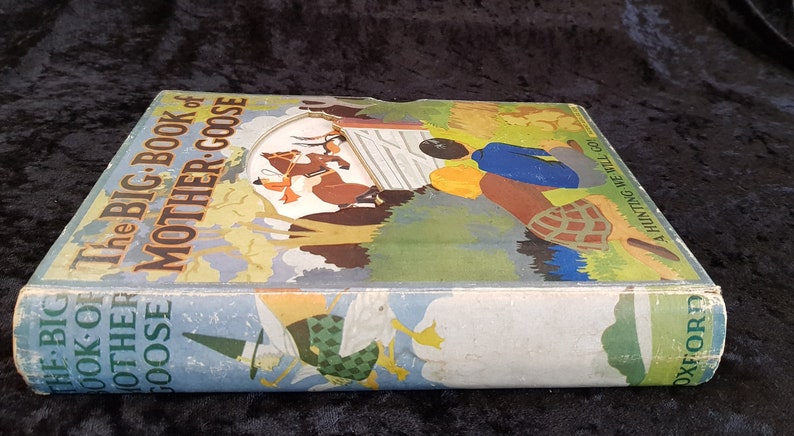 Op de afbeelding: Een vintage hardcover boek getiteld "The Big Book of Mother Goose". De omslag toont kleurrijke illustraties van kinderrijmkarakters en sc&egrave;nes. De rug van het boek toont de titel en de naam van de uitgever, Oxford.