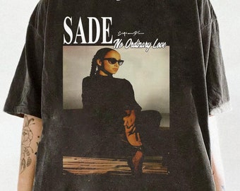 May include: Black t-shirt with a faded look featuring a graphic of Sade with the text "SADE" and "No Ordinary Love" printed on the front.