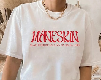 Könnte beinhalten: Weißes T-Shirt mit einem roten grafischen Aufdruck des Wortes "Måneskin" in einer stilisierten Schriftart. Der Text "Siamo fuori di testa, ma diversi da loro" ist unter dem Bandnamen gedruckt.