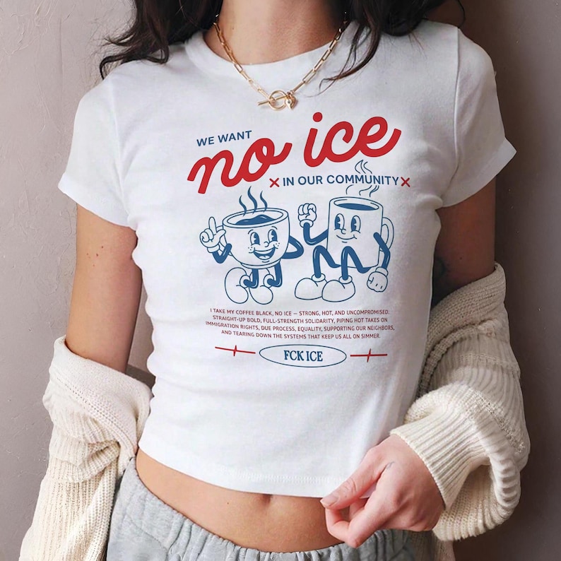 Puede incluir: Camiseta blanca con el texto rojo "WE WANT no ice X IN OUR COMMUNITY X" y dos tazas de caf&eacute; de dibujos animados. La parte inferior de la camiseta tiene el texto "FCK ICE". La camiseta tambi&eacute;n tiene texto adicional.