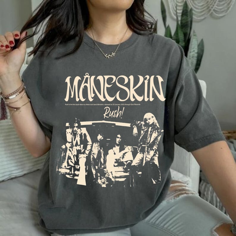 May include: A gray t-shirt with a vintage-style graphic of the band M&aring;neskin. The graphic includes the band's name, the album title "Rush!" and a black and white image of the band members.