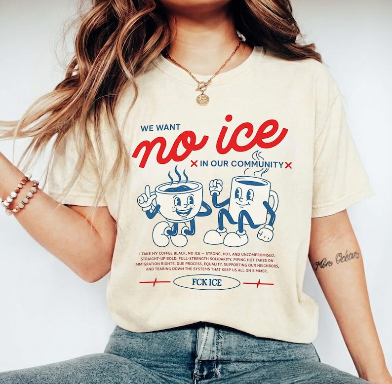Puede incluir: Camiseta color crema con el texto "WE WANT no ice" en escritura roja. Debajo, dos tazas de caf&eacute; de dibujos animados. La camiseta tambi&eacute;n presenta texto sobre los derechos de inmigraci&oacute;n y la frase "FCK ICE."