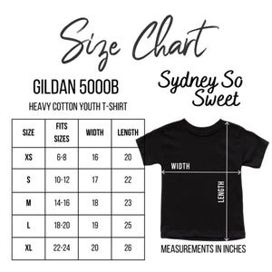 Puede incluir: Camiseta negra para j&oacute;venes con una tabla de tallas. La tabla enumera las tallas XS a XL, con las medidas de ancho y largo en pulgadas. Tambi&eacute;n se ve el texto "Sydney So Sweet".
