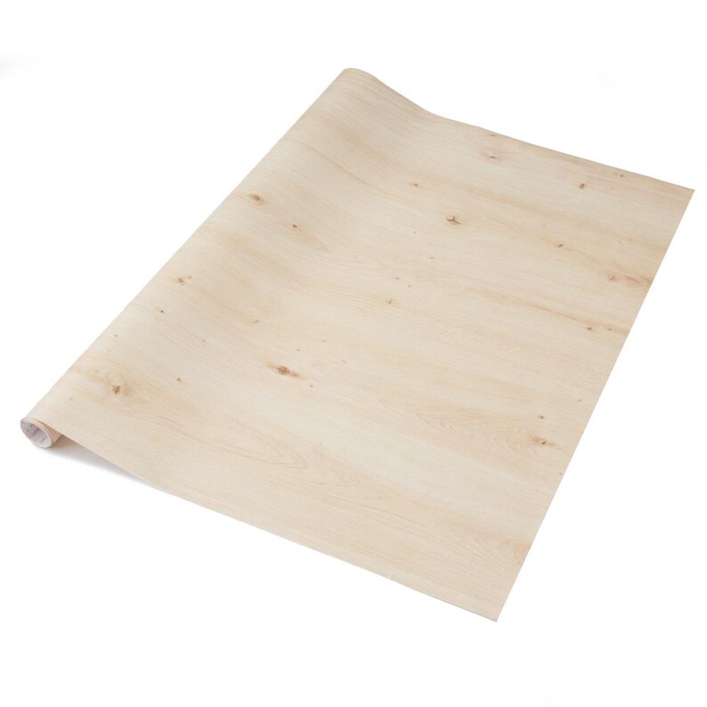May include: A roll of light-colored wood-look contact paper. The paper is unrolled, revealing a wood grain pattern with knots and variations in color. The paper is a light beige color, with darker brown knots.