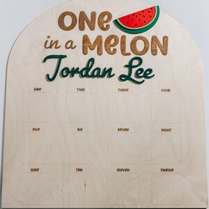 Może przedstawiać: Drewniany znak z grafiką arbuza i tekstem "ONE in a MELON Jordan Lee". Znak ma 12 pustych kwadrat&oacute;w oznaczonych liczbami od jeden do dwanaście.