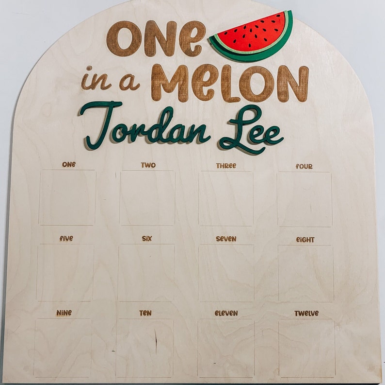 Może przedstawiać: Drewniany znak z grafiką arbuza i tekstem "ONE in a MELON Jordan Lee". Znak ma 12 pustych kwadrat&oacute;w oznaczonych liczbami od jeden do dwanaście.
