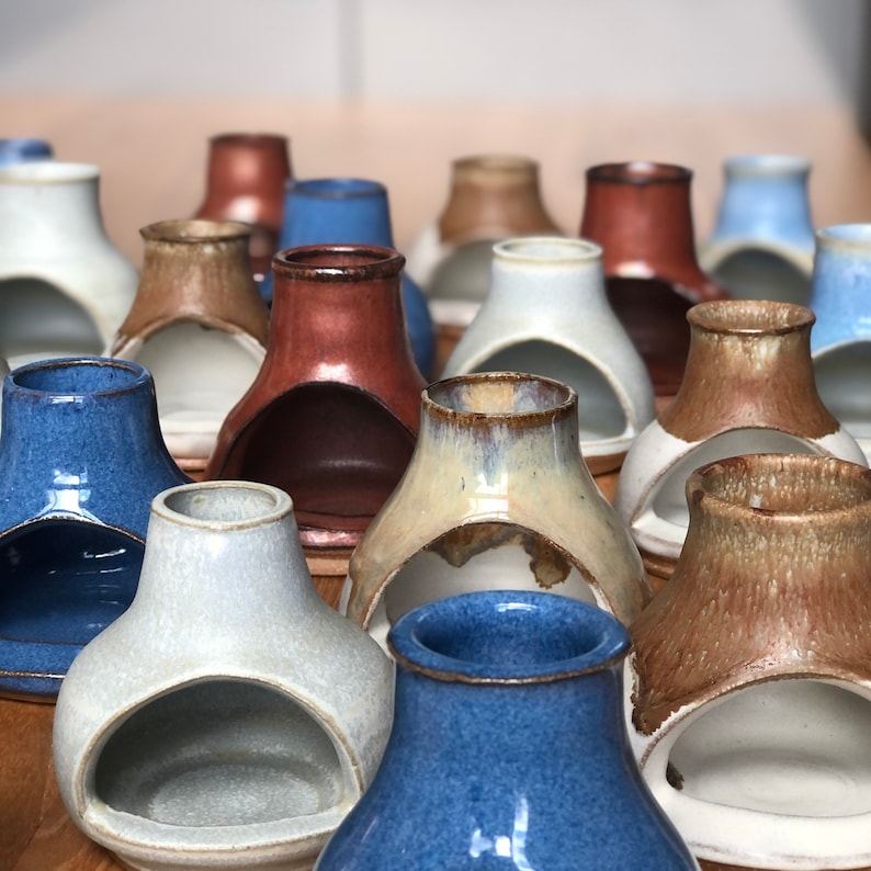 Puede incluir: Una colecci&oacute;n de portavelas de cer&aacute;mica en varios colores, incluyendo azul, marr&oacute;n, blanco y rojo. Los portavelas tienen un dise&ntilde;o &uacute;nico con un recorte en el centro, perfecto para sostener una vela de t&eacute; o una vela votiva.