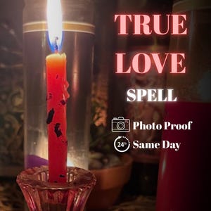 May include: A burning red candle in a pink glass holder, with the text "TRUE LOVE SPELL". The candle has black marks and a blue and yellow flame. Other objects are visible in the background.