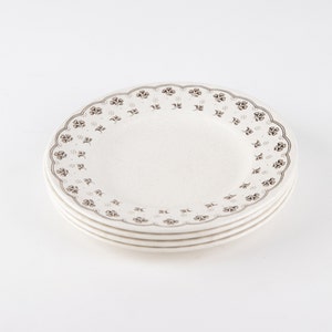 May include: A set of three white ceramic plates with a brown floral pattern around the edge.
