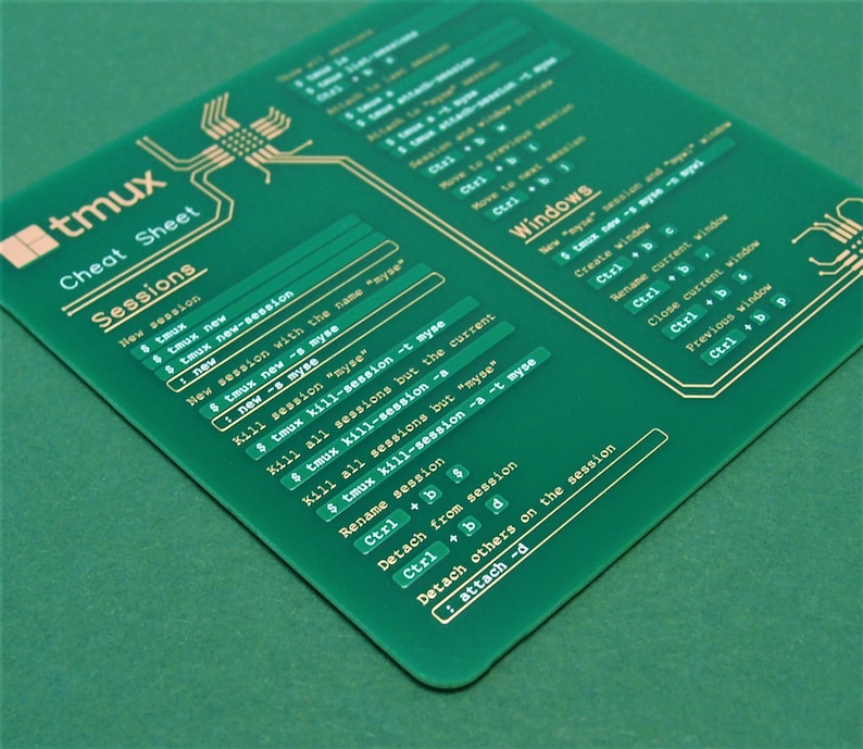 May include: A green plastic cheat sheet with gold lettering for the tmux terminal multiplexer. The cheat sheet includes commands for creating, renaming, and killing sessions and windows. It also includes commands for detaching and attaching to sessions.