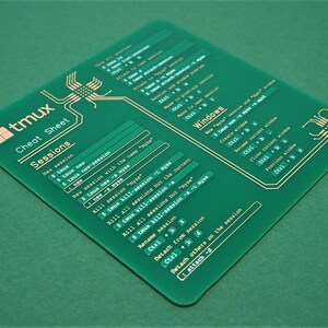 May include: A green plastic cheat sheet with gold text for the tmux terminal multiplexer. The cheat sheet includes commands for sessions and windows.
