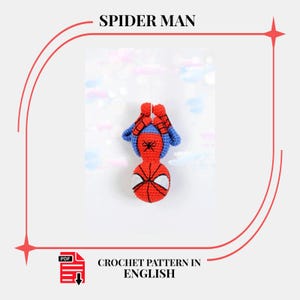 Op de afbeelding: Een gehaakte Spider-Man pop, voornamelijk rood met blauwe details, hangend ondersteboven. De pop heeft het maskerontwerp van het personage met witte oogvormen. De tekst "SPIDER MAN" en "CROCHET PATTERN IN ENGLISH" is ook zichtbaar.