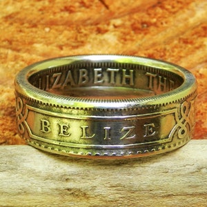 May include: A silver ring made from a Belizean coin. The ring features the words "Elizabeth the" and "Belize" on the band.