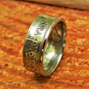 May include: A silver coin ring with the year 1943 engraved on the side. The ring is made from a silver coin and has a smooth, polished finish.