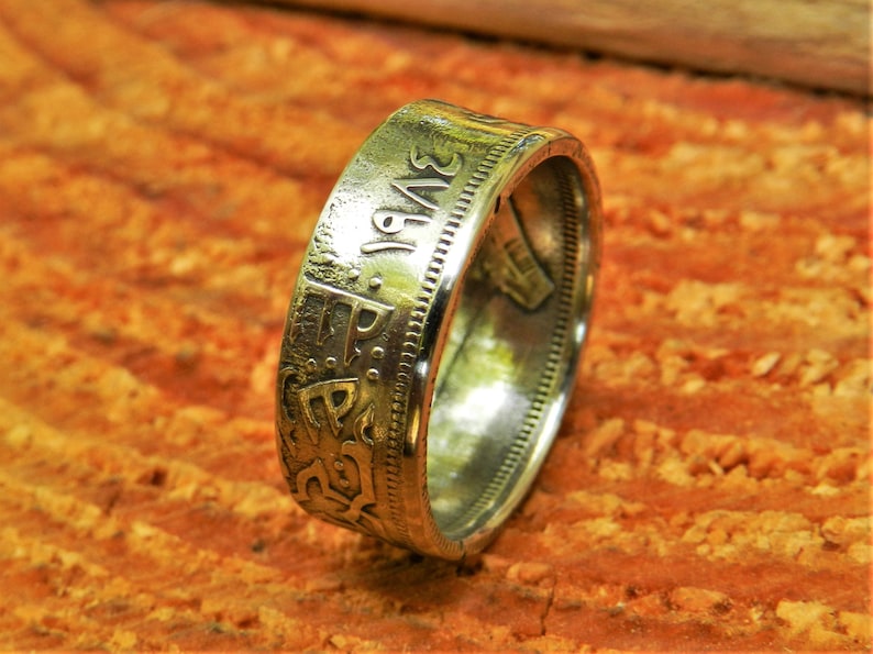 May include: A silver coin ring with the year 1943 engraved on the side. The ring is made from a silver coin and has a smooth, polished finish.