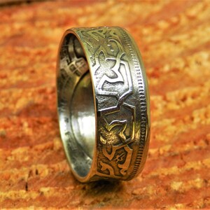 May include: A silver ring made from a vintage coin with an intricate Celtic knot design.