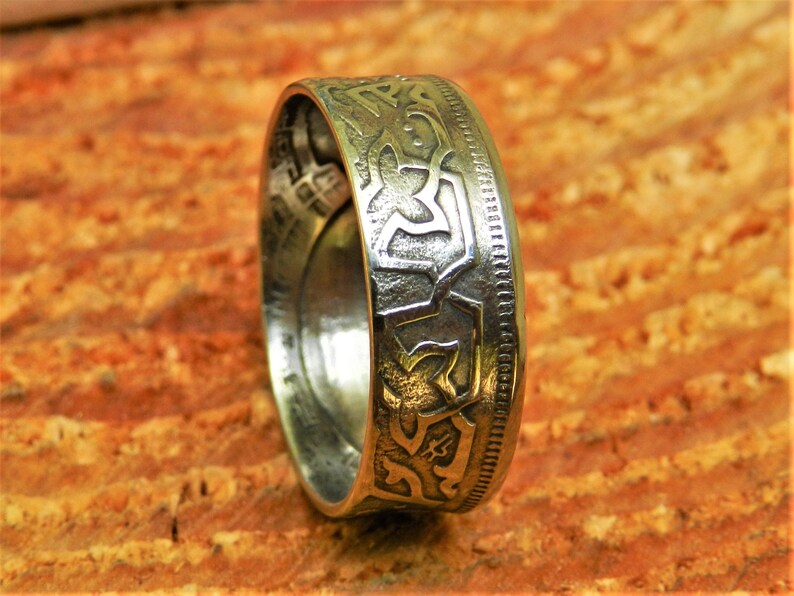 May include: A silver ring made from a vintage coin with an intricate Celtic knot design.