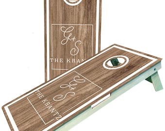 May include: Two wooden cornhole boards with a light brown wood grain design. Each board has a white border and a circular hole. The boards display the text "G+S THE KRANTZ" in a white, elegant font.