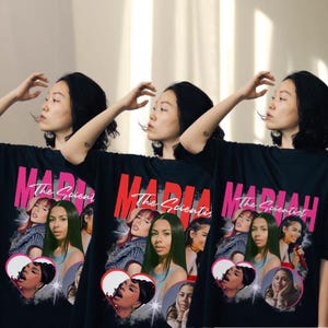 May include: Black t-shirts with a graphic of the singer Mariah and the text "MARIAH The Scientist". The graphic includes images of the singer and a heart shape.