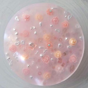 May include: A pink resin tray with a variety of small pink and white flowers and silver glitter embedded in the resin.