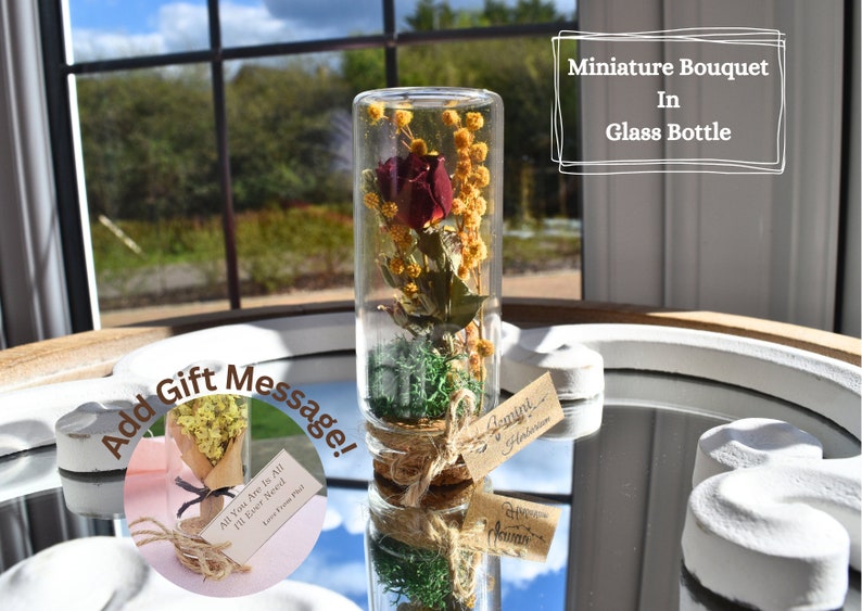 A bouquet of red rose, complemented with yellow mimosa and green moss, all placed beautifully in a glass cork bottle.