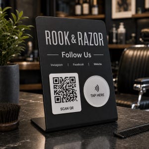 Peut inclure: Un panneau noir en forme de L avec le texte blanc ROOK & RAZOR, Follow Us, Instagram, Facebook et Website. Il comprend un QR code carré blanc avec le texte SCAN QR et une icône circulaire blanche avec un symbole de signal et le texte TAP HERE.