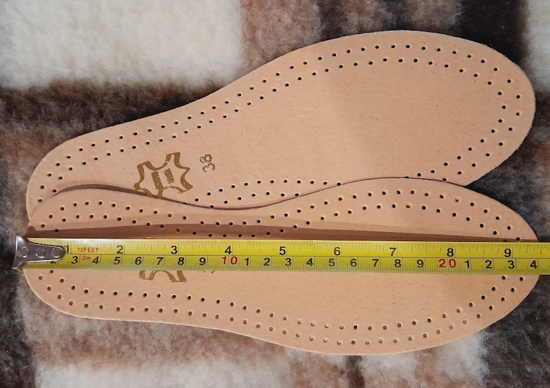 May include: Two beige leather insoles with a perforated pattern. The insoles are sized 38 and measure 10 inches in length.