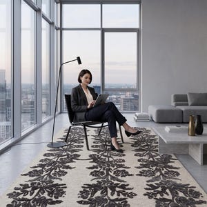 May include: A rectangular area rug featuring a light beige base with three vertical columns of dark charcoal floral and botanical patterns. The rug has a textured, raised pile design that creates a distinct contrast against the neutral background.