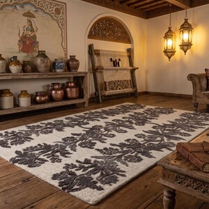 May include: A rectangular area rug featuring a cream-coloured base with a repeating dark grey floral pattern. The design consists of symmetrical, stylised botanical motifs arranged in vertical columns across the surface of the textile floor covering.
