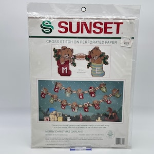 Può includere: Modello di punto croce per una ghirlanda di Buon Natale con una fila di orsacchiotti che tengono lettere che compongono la scritta "Buon Natale". Il modello è su carta perforata e include istruzioni per cucire la ghirlanda.