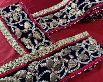 May include: Blue velvet trim with gold and silver embroidery, featuring a leaf design. The trim has a red and green border.