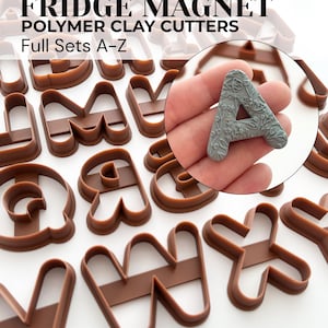 Puede incluir: Una colección de cortadores de arcilla polimérica marrón con forma de letras de la A a la Z, etiquetados FRIDGE MAGNET POLYMER CLAY CUTTERS Full Sets A-Z. Un recuadro circular muestra una letra A gris con un patrón floral detallado en relieve.