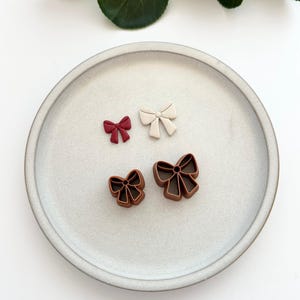 Puede incluir: Tres lazos de diferentes colores en un plato blanco. Los lazos son rojo, blanco y marrón.