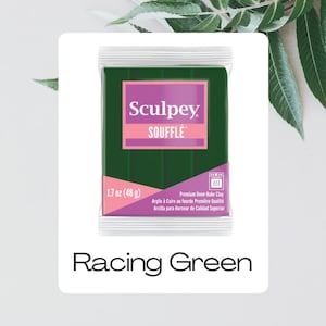 May include: A package of Racing Green Sculpey Soufflé oven-bake clay. The package features a dark green block of clay with a pink and white label. The label reads "Sculpey Soufflé" and "1.7 oz (48 g)".