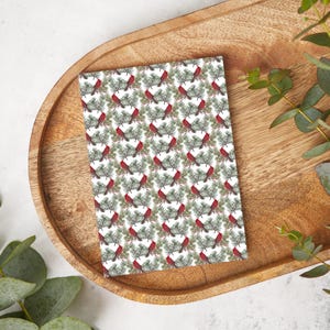 May include: A white card with a repeating pattern of red cardinals perched on green pine branches with red berries.
