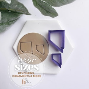 Può includere: Due tagliabiscotti in plastica viola a forma dello stato del Nevada. I tagliabiscotti sono su una superficie esagonale bianca. Il testo "new sizes" è scritto in nero su un cerchio bianco. Il testo "keychains, ornaments & more" è scritto in nero su un rettangolo bianco. Il testo "bh" è scritto in nero su un rettangolo bianco. Il testo "polymer clay supply" è scritto in nero su un rettangolo bianco.